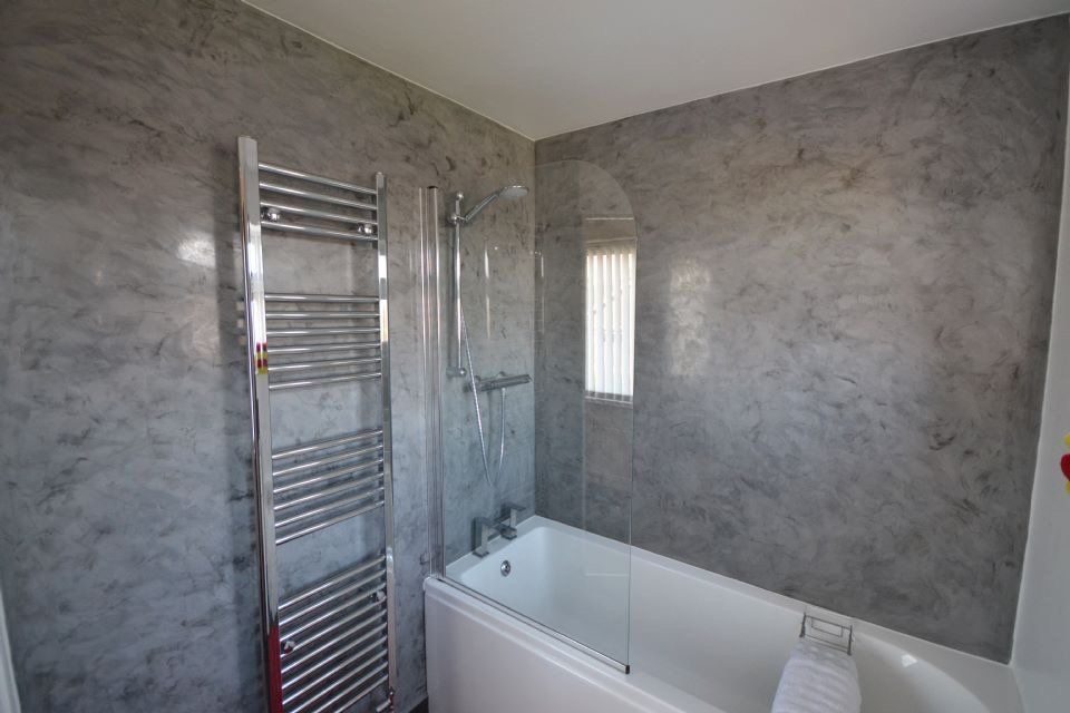 Badezimmer mit grauer Marmorputz-Wand und Handtuchheizkörper