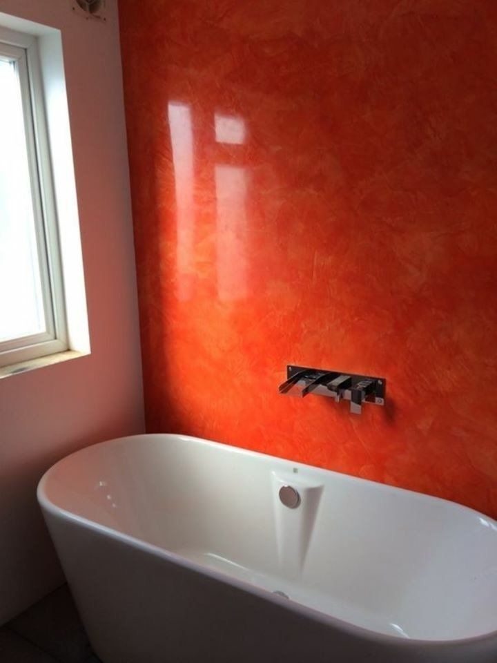 Rote Stuccolustro-Wand hinter einer freistehenden weißen Badewanne