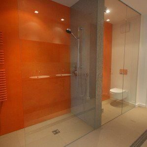Dusche mit orangefarbener Stuccolustro-Wand und Glastrennwand