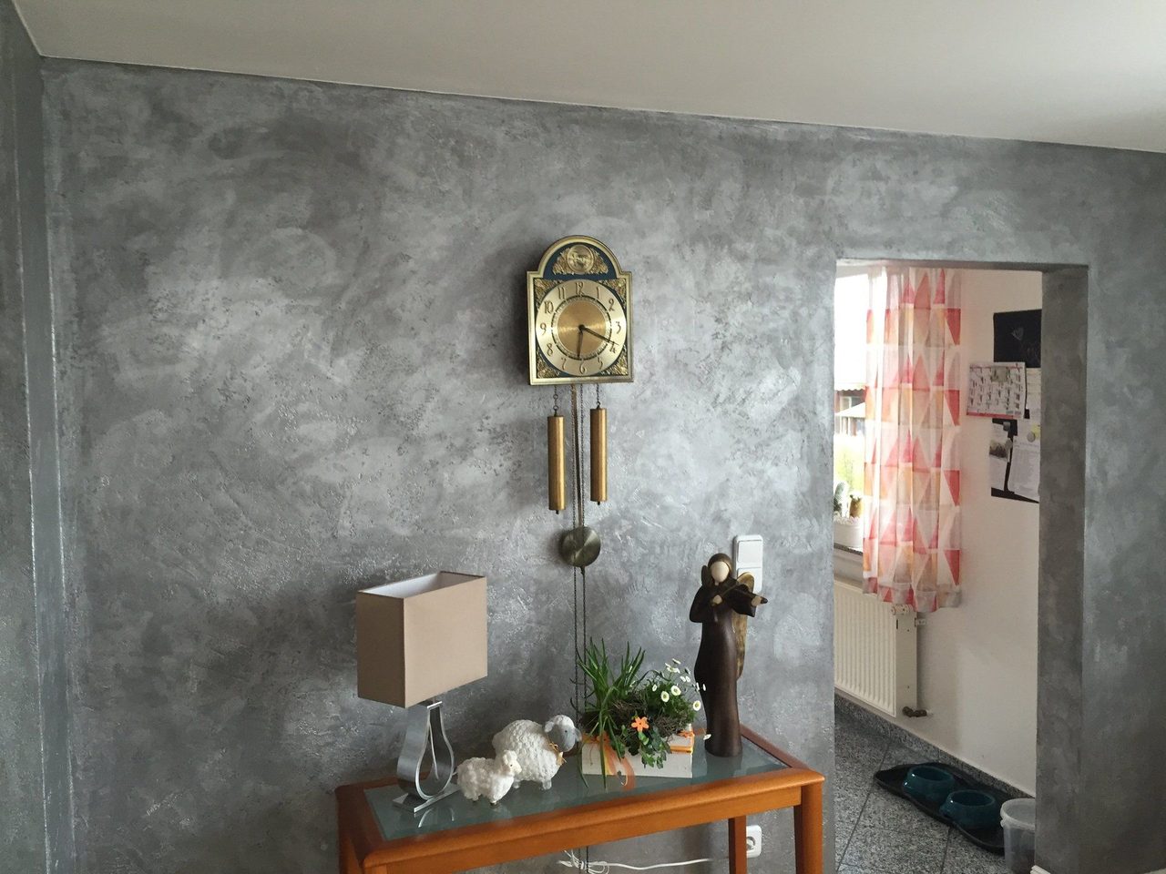 Flur mit grau gespachtelter Wand und Standuhr