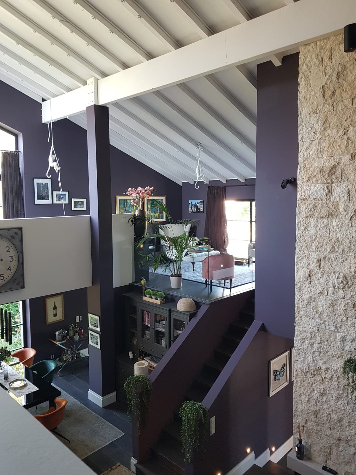Treppenhaus mit aubergine gestrichener Wand und Natursteinfläche