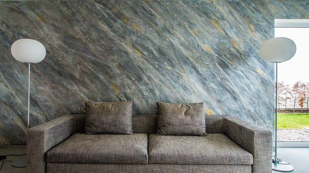 Wohnzimmer mit Marmorlasur in Blaugrau, davor ein graues Sofa und zwei Stehlampen
